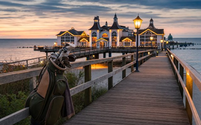 Abendstimmung an einer Seebrücke auf Rügen nach einem Golftag, warme Lichter, ruhige Ostsee in der Dämmerung
